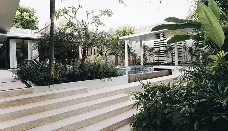 Ambergris Villa, Nusa Dua, Bali — white modern stone stairs descend through tropical landscaping to swimming pool and architectural gazebo | The Luxury Bali