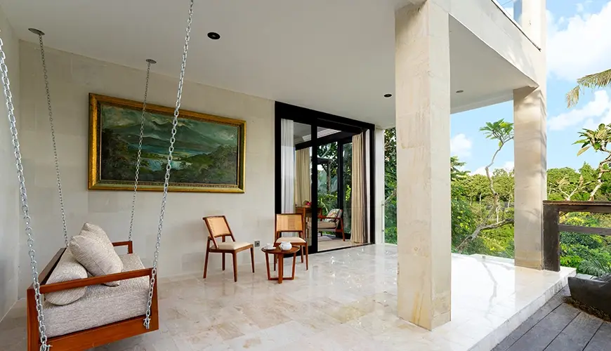 Le Sunset, Ubud, Bali — bright open maharani balcony area with stone flooring featuring a wooden swing sofa and sweeping forest | The Luxury Bali