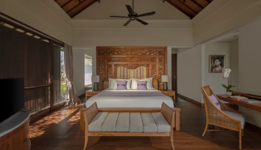 Shanti Residence, Nusa Dua, Bali — luxurious villa bedroom featuring an ornate wooden headboard and sliding glass doors leading to a balcony | The Luxury Bali