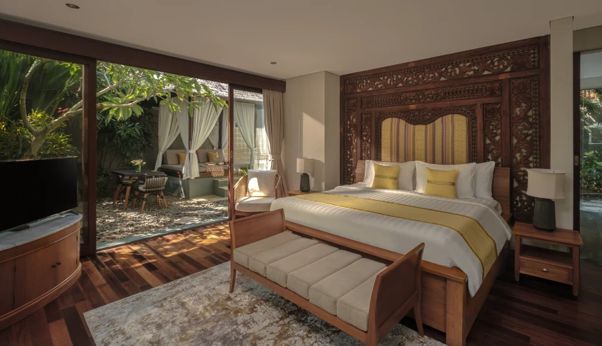 Shanti Residence, Nusa Dua, Bali — luxurious villa bedroom with an ornate wooden headboard and sliding doors opening to a private tropical | The Luxury Bali