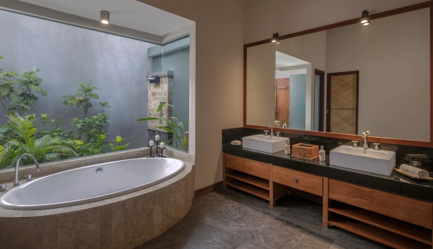 Shanti Residence, Nusa Dua, Bali — modern villa bathroom with double vanity sinks and a soaking tub beside a lush private garden | The Luxury Bali