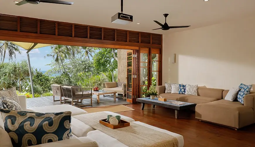 The Cove Bali, Tabanan, Bali — open living room features comfortable sofas and direct outdoor ocean access | The Luxury Bali