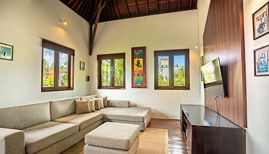 Tropical Svasti Villa, Canggu, Bali — comfortable room with sectional and wooden accent wall | The Luxury Bali