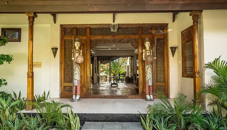Tropical Svasti Villa, Canggu, Bali — traditional villa entrance with carved wooden doors and statues | The Luxury Bali