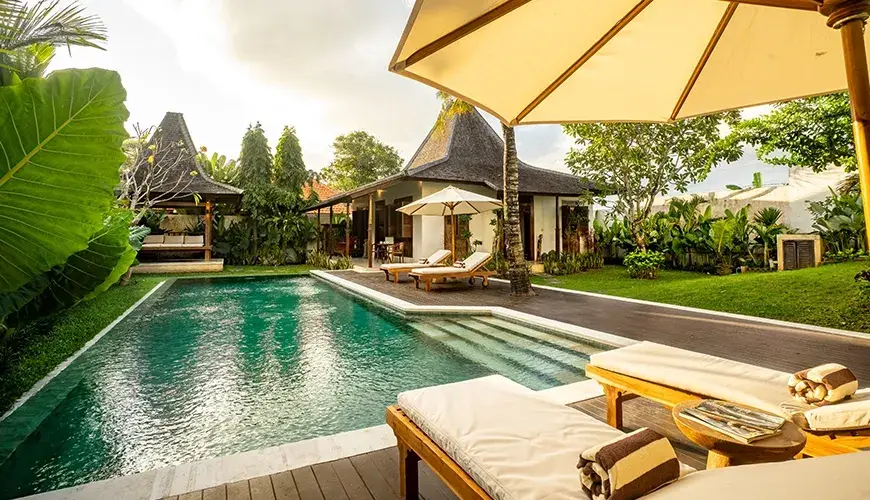 Tropical Svasti Villa, Canggu, Bali — pool area with sun loungers and traditional gazebos | The Luxury Bali