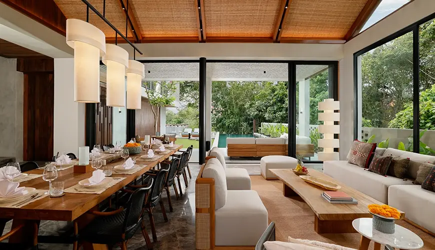 Uma Santai Canggu, Canggu, Bali — beautifully decorated living room and dining area with glass doors leading to a private swimming pool | The Luxury Bali