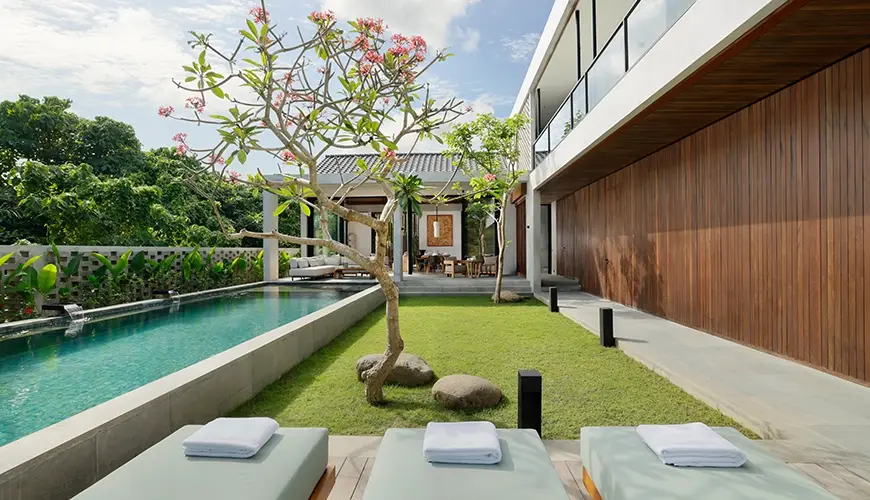 Uma Santai Canggu, Canggu, Bali — bright sunny day showcasing a modern villas beautiful pool with comfortable lounge chairs and lush green | The Luxury Bali