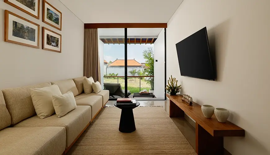 Uma Santai Canggu, Canggu, Bali — minimalist and comfortable entertainment room inside a modern villa with a sofa and flat screen television | The Luxury Bali