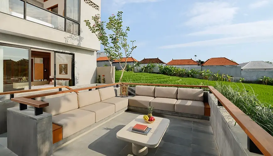 Uma Santai Canggu, Canggu, Bali — stunning sunset deck of a modern villa featuring a cozy outdoor couch with a beautiful rice | The Luxury Bali