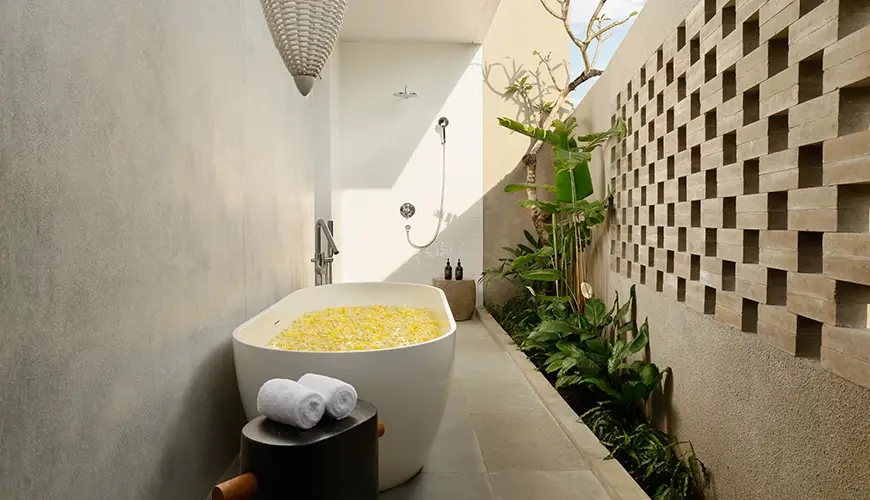 Uma Santai Canggu, Canggu, Bali — stunning villa bathroom with a freestanding bathtub filled with yellow flowers and a luxurious shower | The Luxury Bali