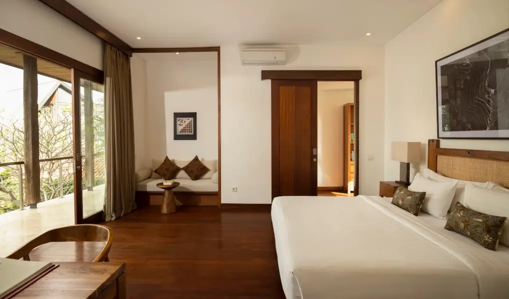 Villa Ambara, Canggu, Bali — comfortable bedroom featuring dark wood floors and balcony access | The Luxury Bali