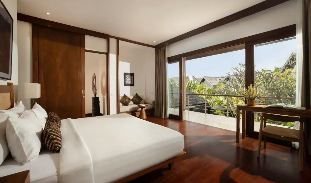 Villa Ambara, Canggu, Bali — tropical bedroom with rich wood flooring and a beautiful balcony view | The Luxury Bali