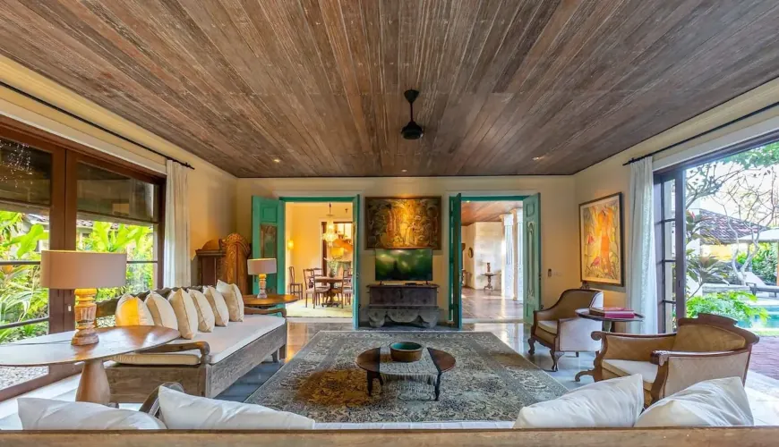 Villa Angsa, Sanur, Bali — spacious living area with tropical wooden ceilings comfortable sofas and a view to the pool | The Luxury Bali