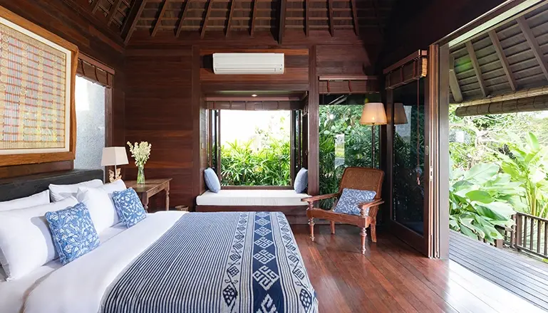 Villa Bangkuang, Canggu, Bali — cozy villa bedroom with a private balcony a comfortable window sofa and tasteful blue and wood | The Luxury Bali