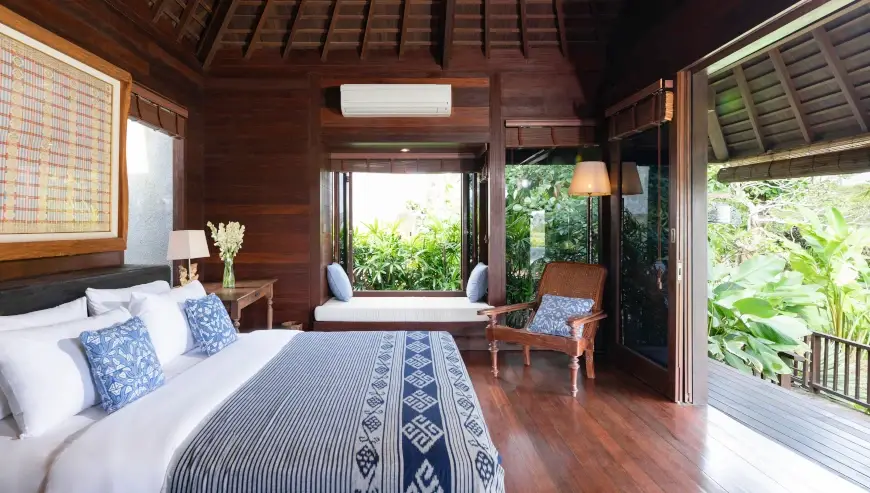 Villa Bangkuang, Canggu, Bali — cozy wooden bedroom with a window seat and lush garden view | The Luxury Bali