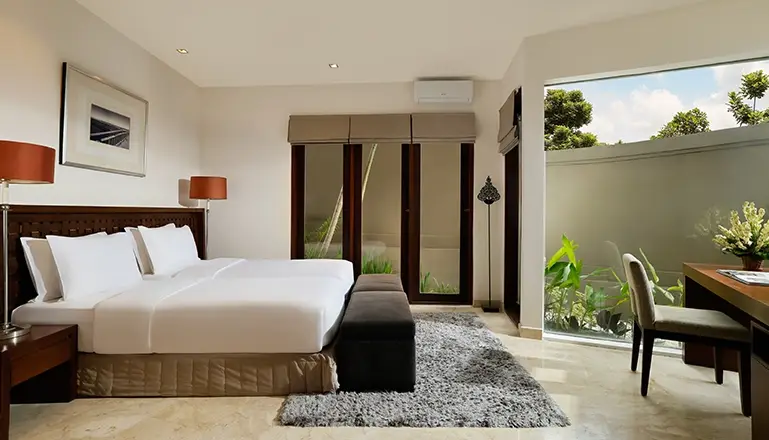 Villa Oshra, Canggu, Bali — bedroom with two twin beds grey bench and garden views | The Luxury Bali