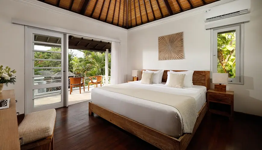Villa Swarna, Seminyak, Bali — cozy villa bedroom featuring a king sized bed and a private balcony with two comfortable chairs | The Luxury Bali