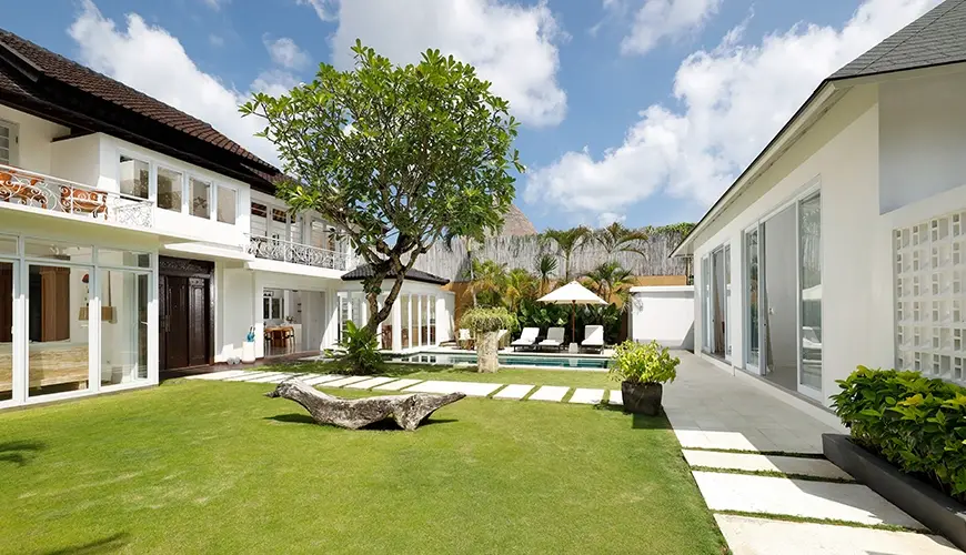 Villa Swarna, Seminyak, Bali — lush green villa garden with pool and stepping stone path | The Luxury Bali