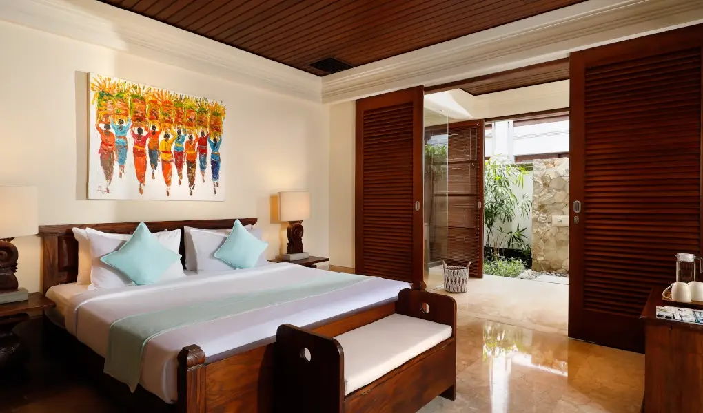 Villa The Seven, Jimbaran, Bali — bedroom with a double bed colorful art and an outdoor shower | The Luxury Bali