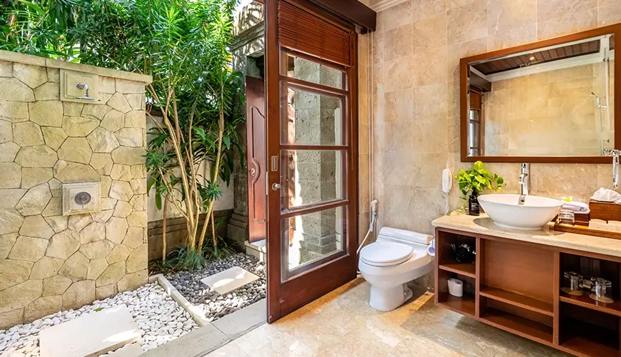 Villa Umarya, Jimbaran, Bali — beautiful villa bathroom with a sink toilet and an outdoor shower with tropical plants | The Luxury Bali