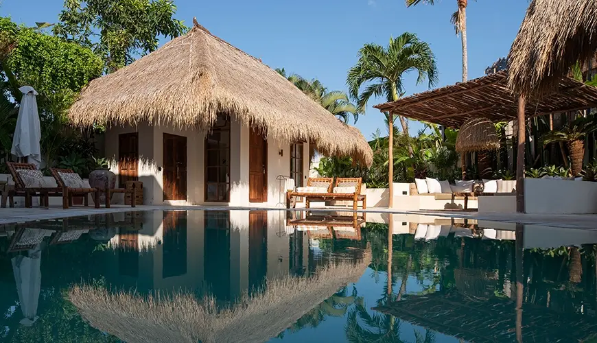 Villa Xanadu, Canggu, Bali — luxurious private villa swimming pool reflecting the gorgeous traditional thatched roof bungalow and tropical lush gardens | The Luxury Bali
