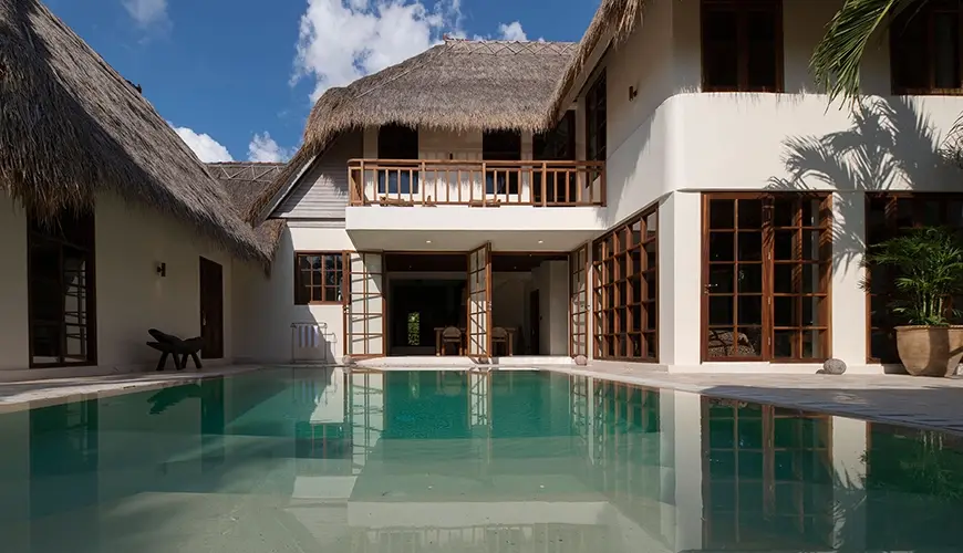 Villa Xanadu, Canggu, Bali — stunning luxury villa exterior featuring traditional thatched roofs and a private swimming pool under a bright | The Luxury Bali