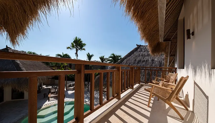 Villa Xanadu, Canggu, Bali — sunny luxury villa balcony overlooking the curved private pool area featuring thatched roofs and comfortable natural | The Luxury Bali