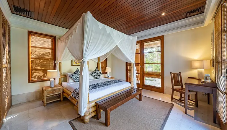 Villa Yasmine, Jimbaran, Bali — bright bedroom features four poster bed opening to lush tropical views | The Luxury Bali