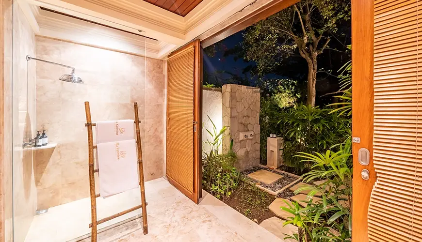 Villa Yasmine, Jimbaran, Bali — luxurious indoor outdoor bathroom featuring with glass shower and illuminated private garden with lush tropical plants | The Luxury Bali