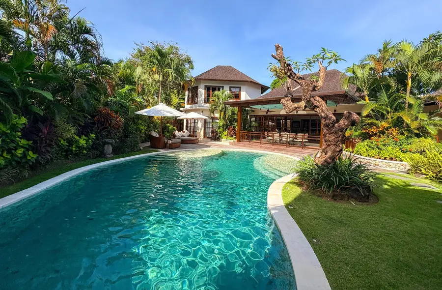 Lataliana, Seminyak, Bali: a curved pool in a tropical garden, with the house behind