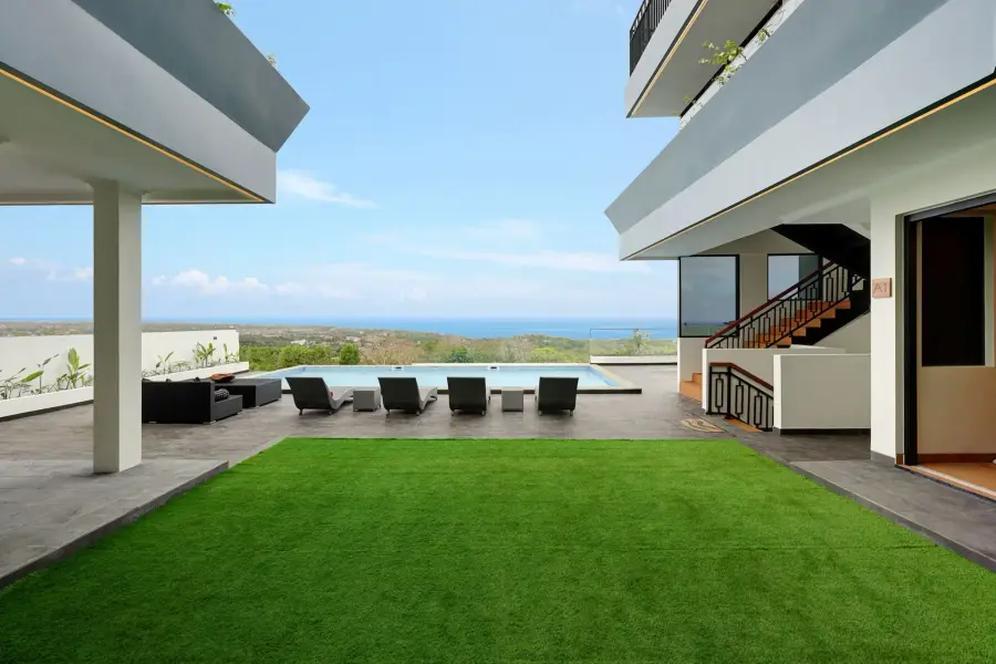 A six-bedroom villa in Uluwatu, Bali: a lawn and terrace with sun loungers, and the ocean on the horizon